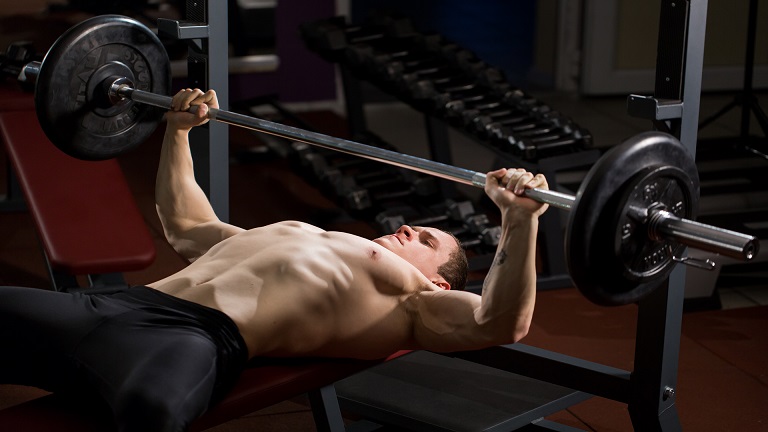 Lifter performing a barbell bench press with proper form on a flat bench