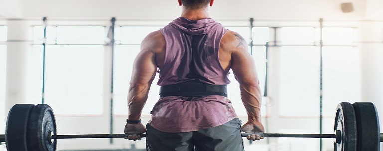 Lifter performing a barbell shrug with shoulders elevated toward the ears