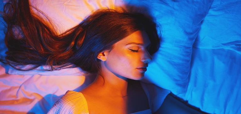 Person lying awake in dim bedroom looking at the ceiling at night